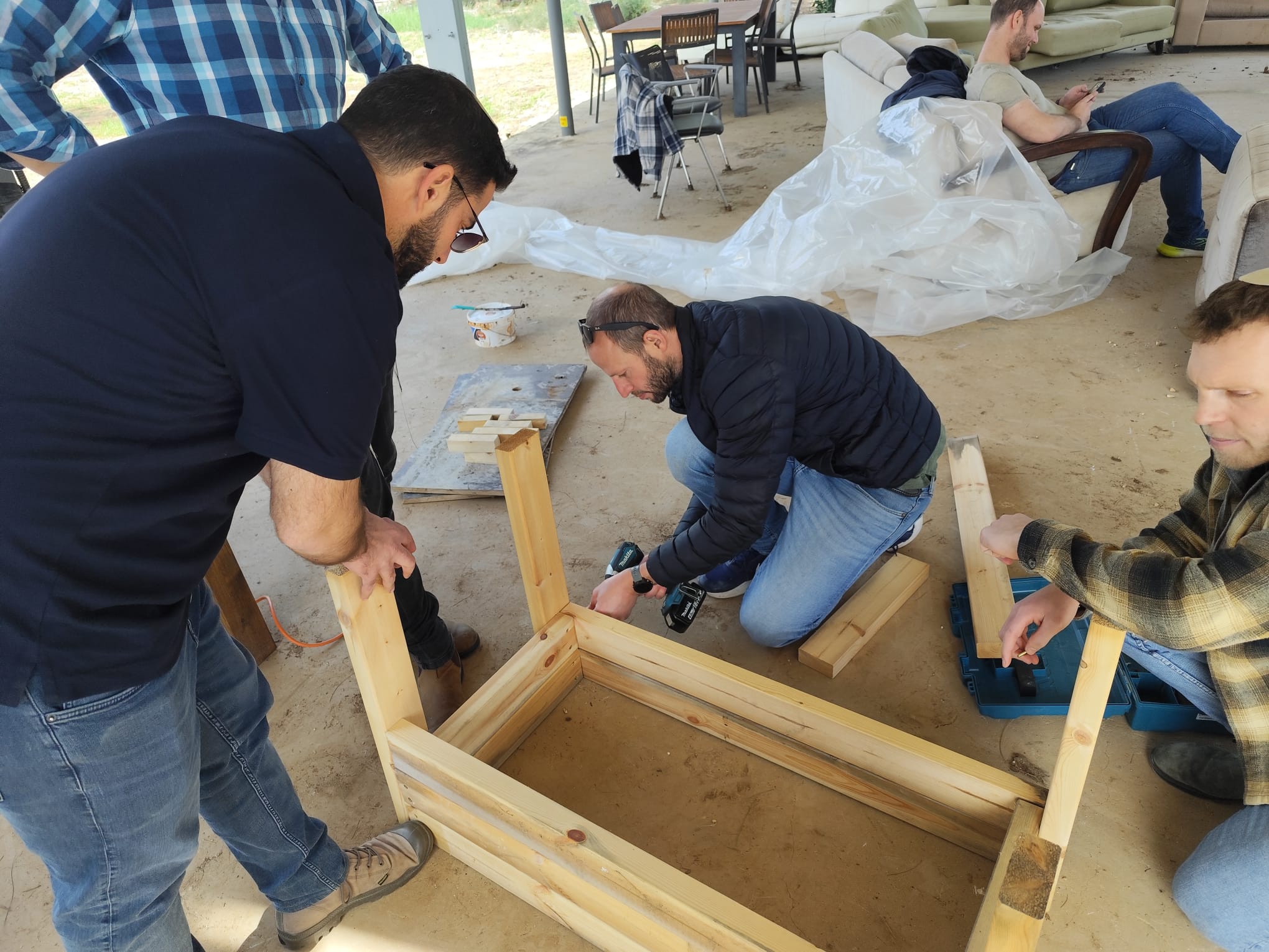 Three participants working on a wooden planter outdoors